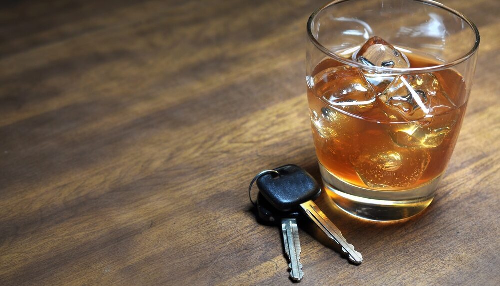 glass of whiskey in ice next to handcuffs and car keys. Let a Providence RI DUI Lawyer help you with your case