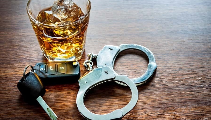glass of whiskey in ice next to handcuffs and car keys. Let a Providence RI DUI Lawyer help you with your case