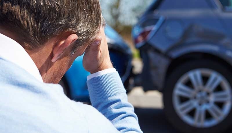 Man with hand on head after a car accident has exceeded his insurance policy limits