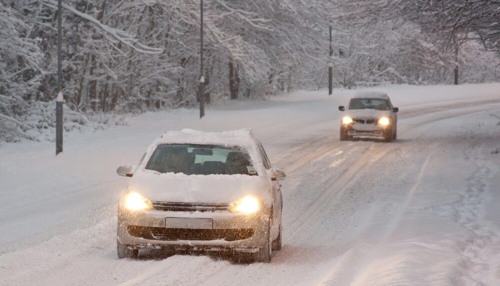 Two cars driving on a snowy road in Rhode Island