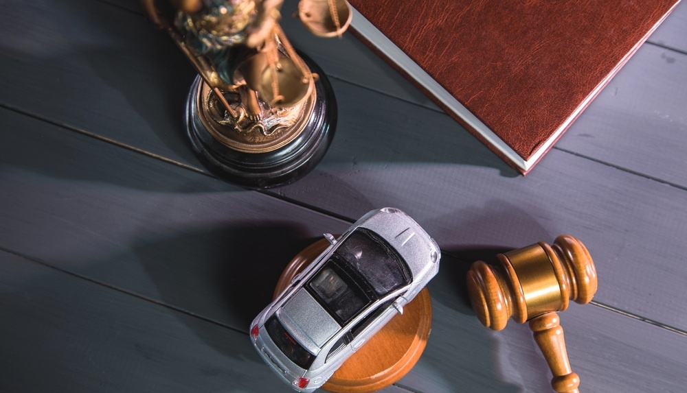 scales of justice, a car, a book, and a gavel on the desk of a car accident lawyer