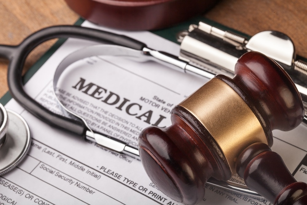 gavel on a lawyer's desk sitting on top of a stethoscope and a medical billing form