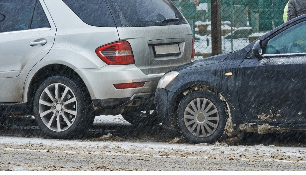 car accident in winter with black car hitting white van in the rear
