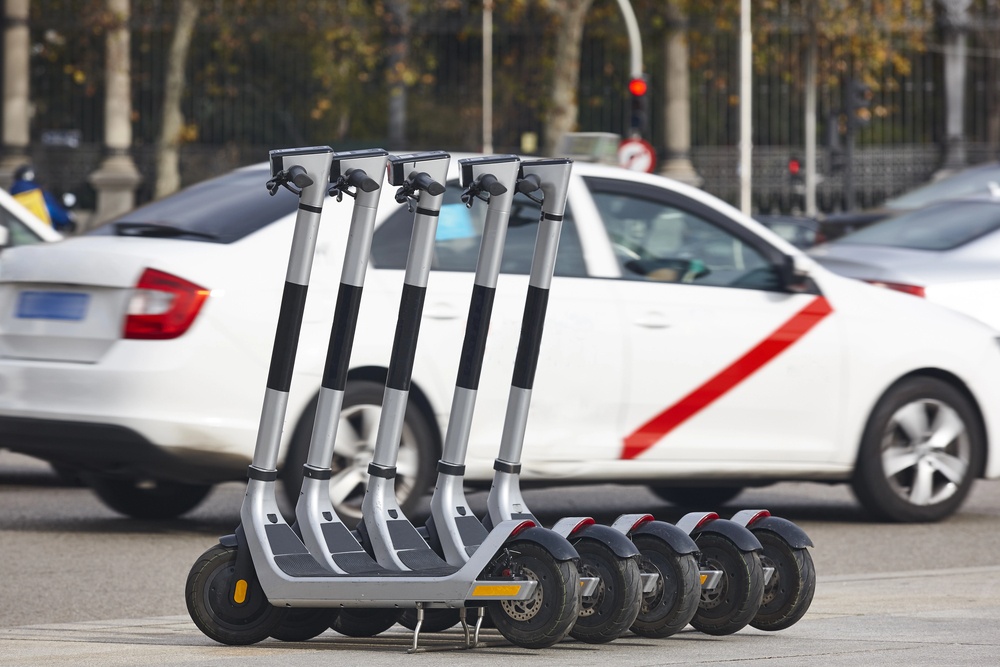 E-scooters lined up on side of road in Providence in front of a car