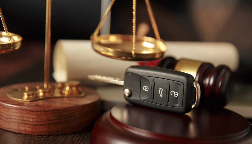 Car key beside a gavel and scales of justice, representing a car accident claim.